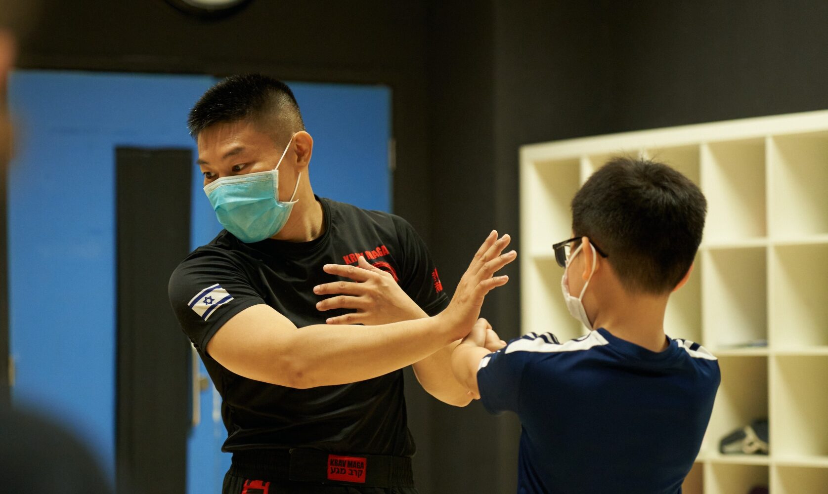 Coach teaching a young boy Krav Maga